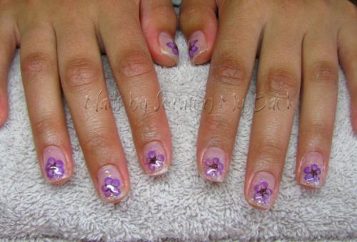 Gel nails embedded with glitter and purple dried flowers