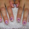 Gel nails embedded with glitter and purple dried flowers